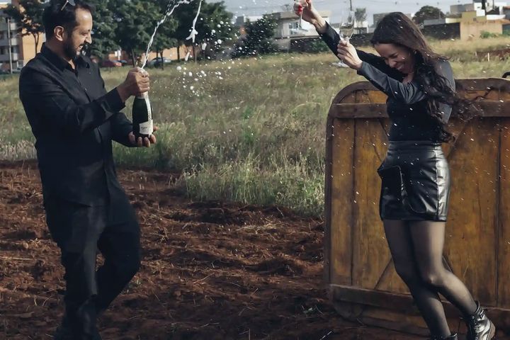 Casal abrindo espumante no campo depois do pouso